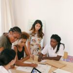 A diverse group of women discussing a project in a modern office setting.